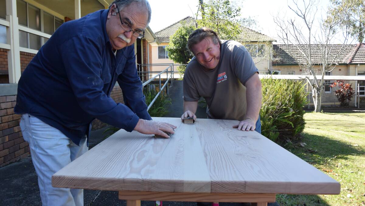 Workmanship pride: Andrew Krotz (right) works methodically to sand the oregon planks and is guided by About Inclusion support worker, Terry Wright. Photo: Ainslee Dennis.