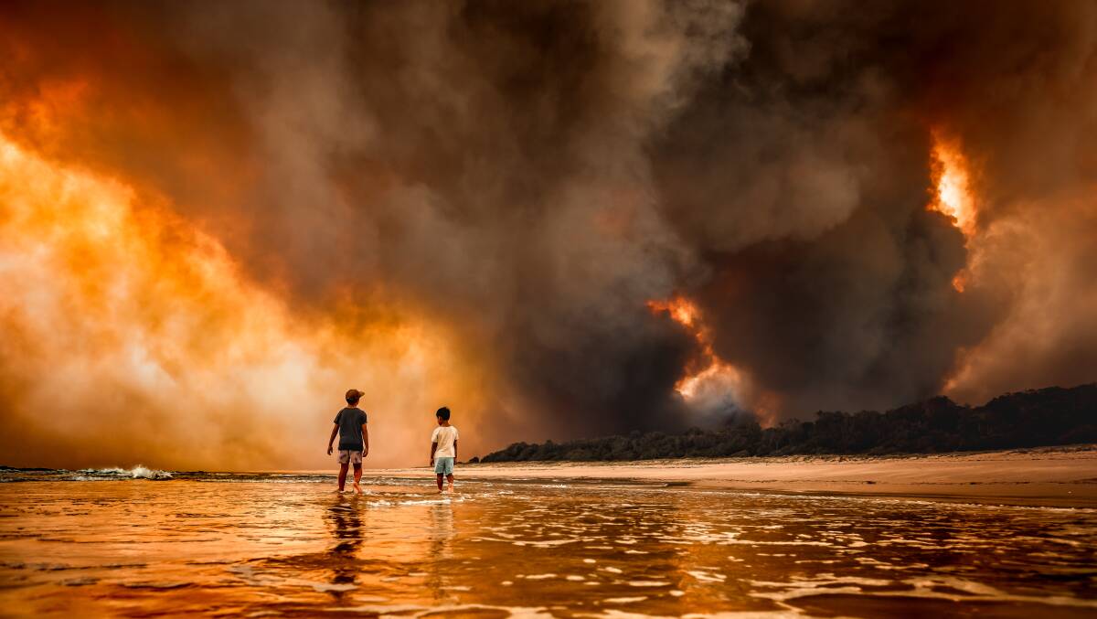 The Iconic Image: Martin Von Stoll's two sons look on as a fire engulfs bushland south of Black Head back beach.