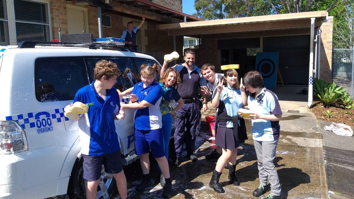 Multi-category students from Bulahdelah Central School helping police officers Ash Ray and Trevor McLeod clean their car.