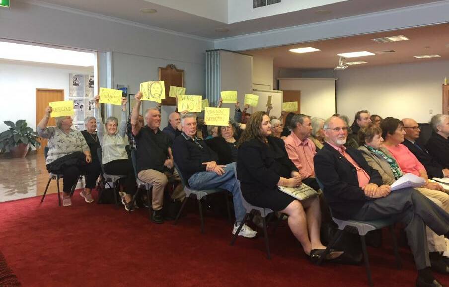  Some members of the gallery at the August 22 ordinary meeting of MidCoast Council held up signs in protest of the 'Barrington Coast' destination name.