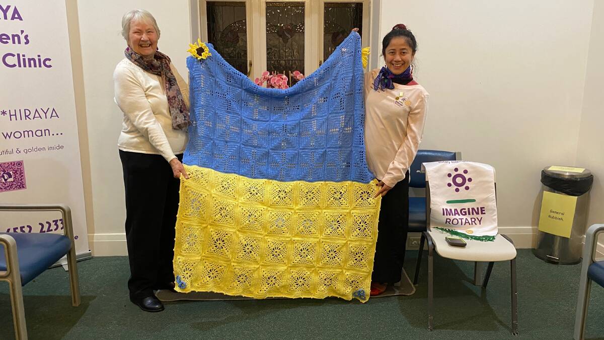 Irene Wann (Ieft) presenting her blanket to Rotary Club of Taree president Dr Grace Maano. Photo: Julia Driscoll