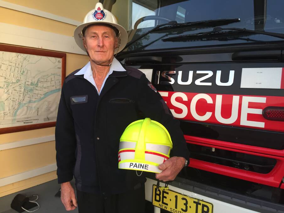 Farewell and thank you: Greg Paine, wearing a helmet from the start of his firefighting career, and holding one from the end. Photo: Julia Driscoll