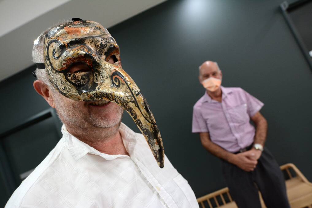 Dr Simon Holliday wearing his 'plague doctor' mask bought on a trip to Venice six years ago, with David Moore wearing a more modern variety. Photo: Scott Calvin