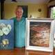 Bed Inn Bus founder Terry Stanton, with the two paintings donated by Ron and Helen Hindmarsh for raffle prizes. Photo: Scott Calvin