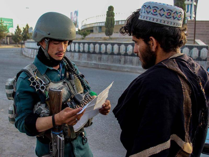 An Afghan security official inspects a local's paperwork at a checkpoint in Kandahar.