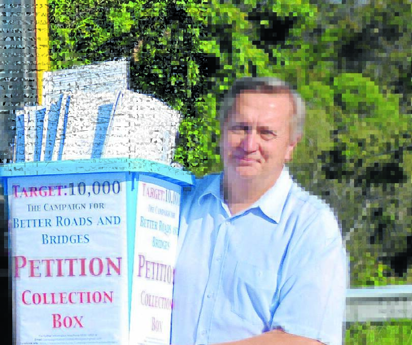 Cr Peter Epov with a bundle of the Better Roads and Bridges petitions.