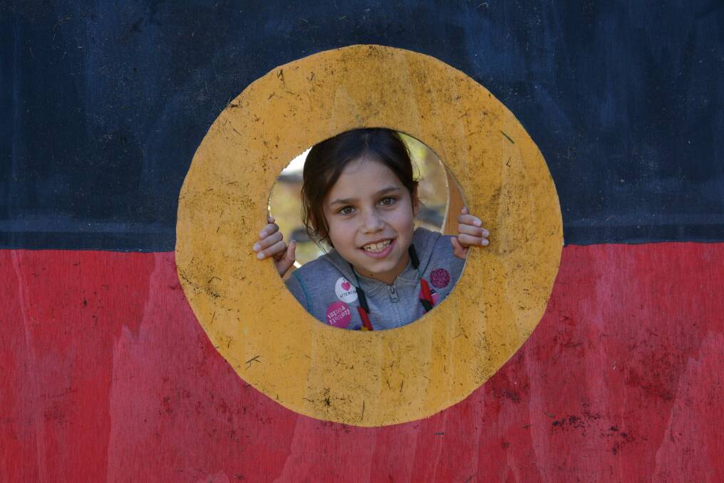 Zara Williams peers out of an Aborignal Flag.