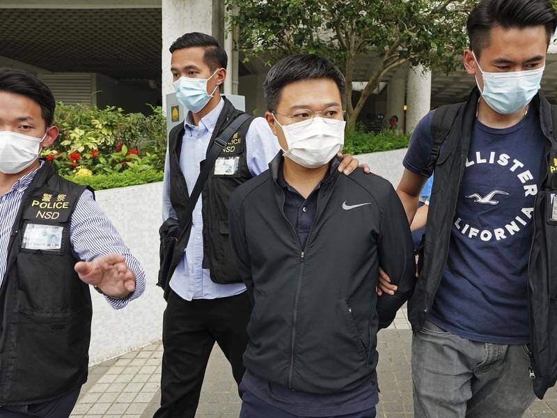 Apple Daily editor-in-chief Ryan Law (second from right) is led away in handcuffs during the raid.
