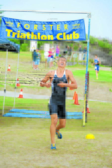 Oh the pain: Jake Schumacher from Forster crosses the line to win the Crowdy Head triathlon last January.