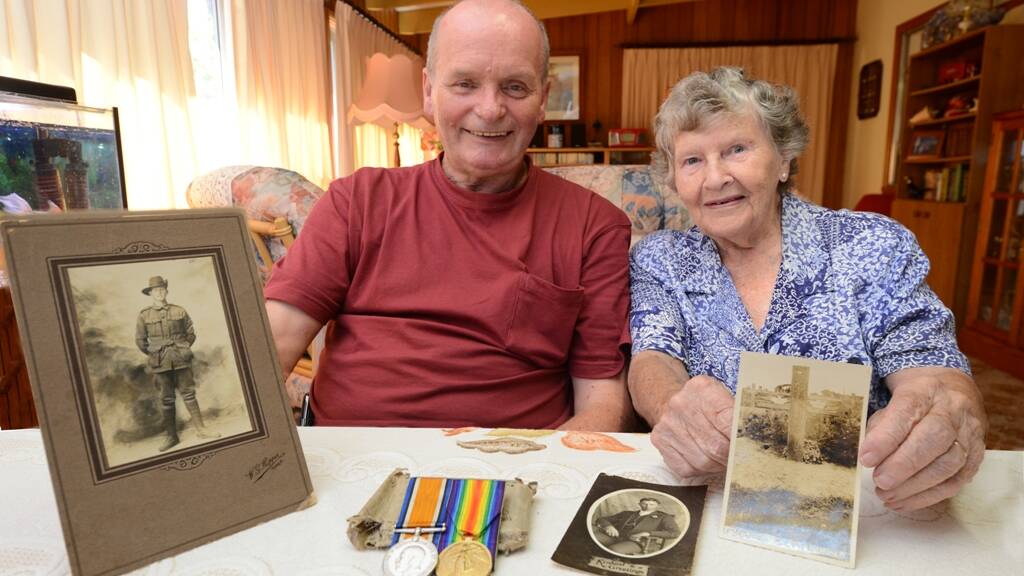 Darcy Elbourne and Marie Black hold photos of Arthur Douglas Elbourne, including his resting place at the Le Treport Military Cemetery in France.