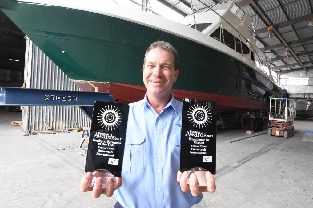 Colin Steber with the regional business award trophies and a resort boat that will be bound for South Africa.