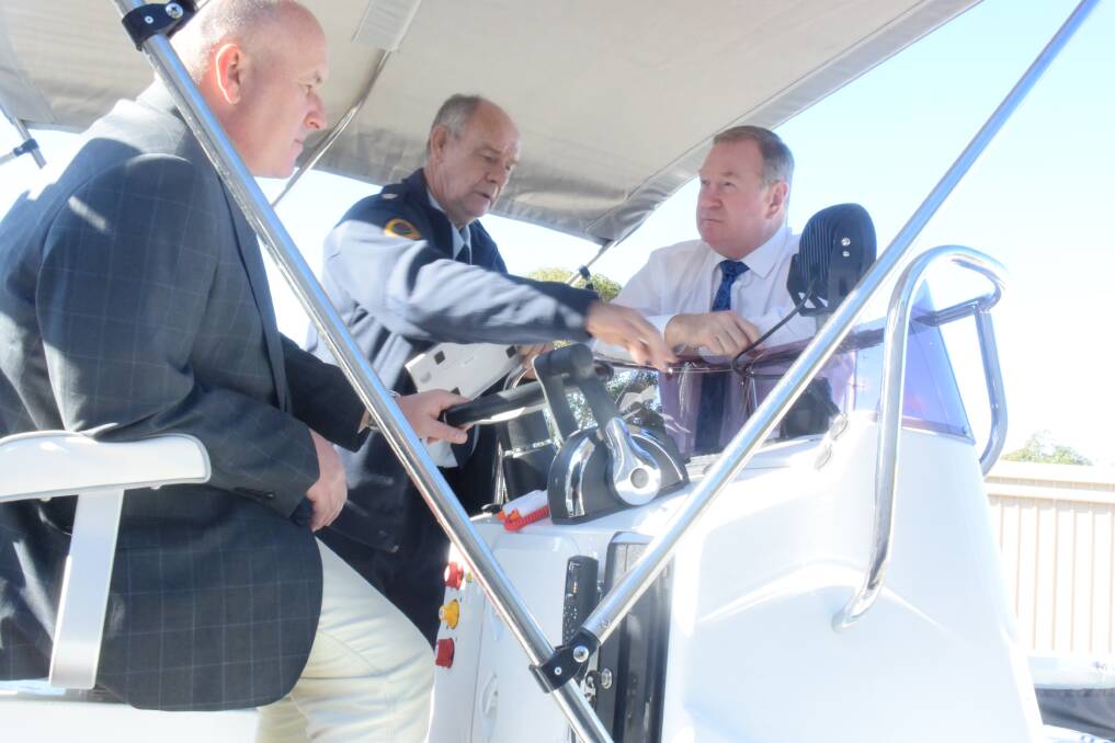 Local commander of the Mid North Coast NSW SES cluster Glenn Laycock shows Police Minister David Elliott and Member for Myall Lakes Stephen Bromhead how the new punt works.
