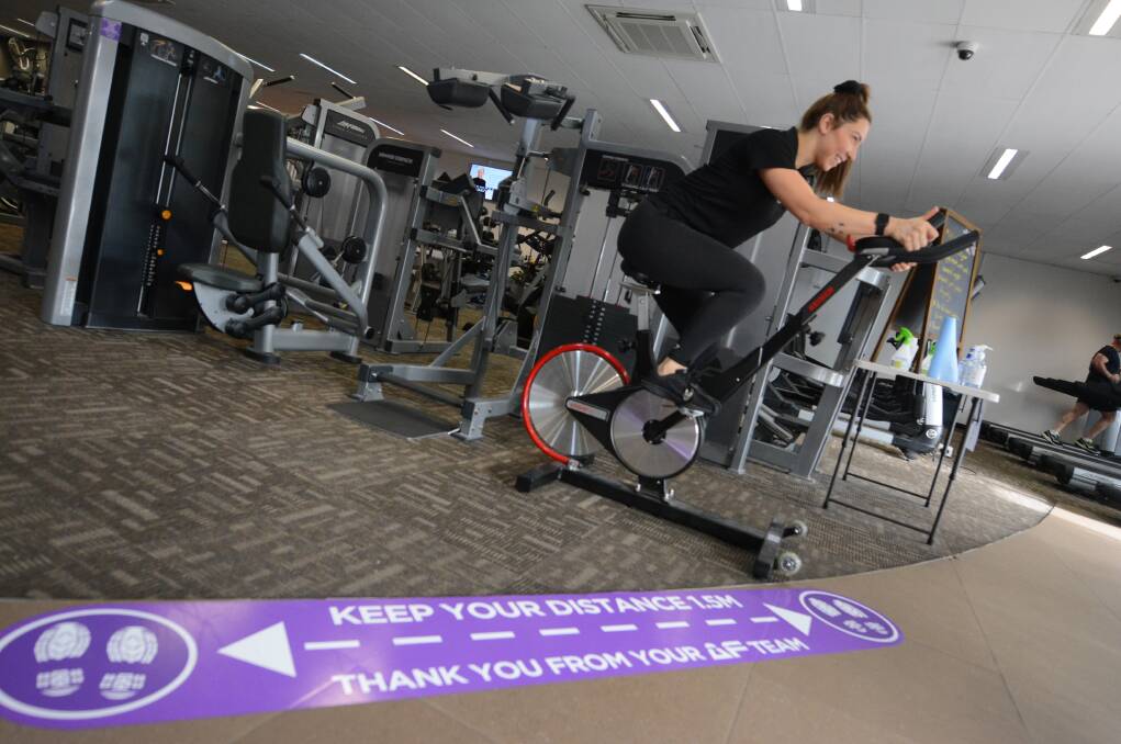Elise works up a sweat on the spin bike while keeping her distance from other gym users. Photo: Scott Calvin.
