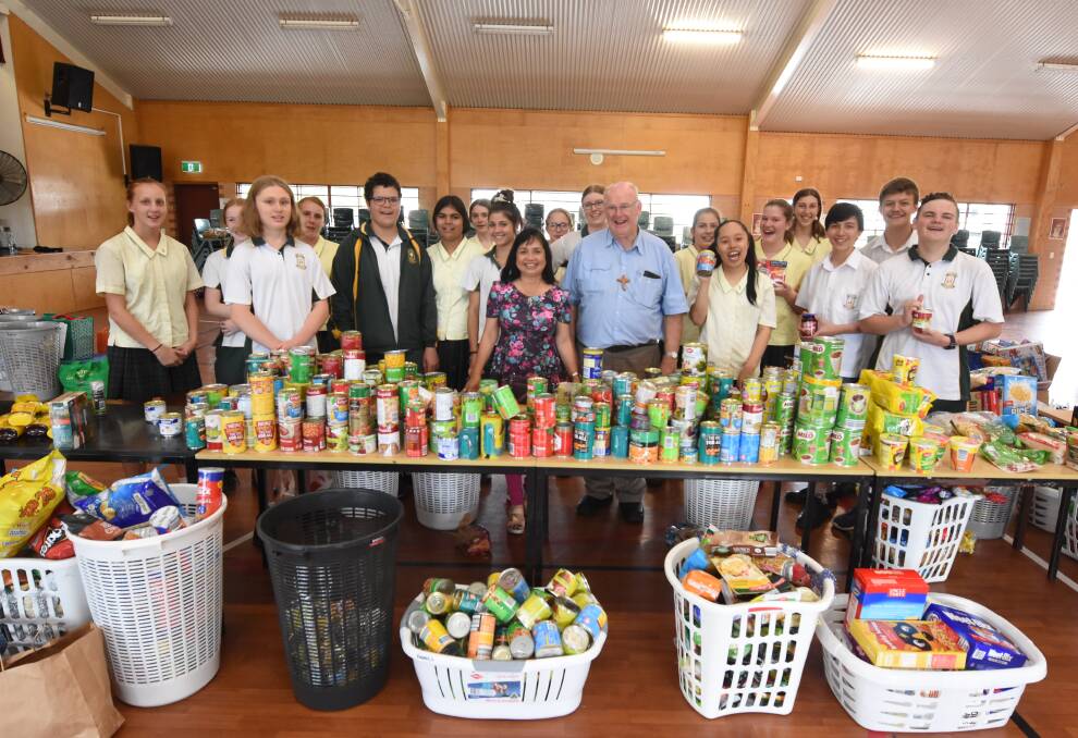 Susie Ploder and Deacon Vince Ryan with year nine St Clare's students as they prepared Christmas hampers for those in need in the community. Photo: Scott Calvin. 