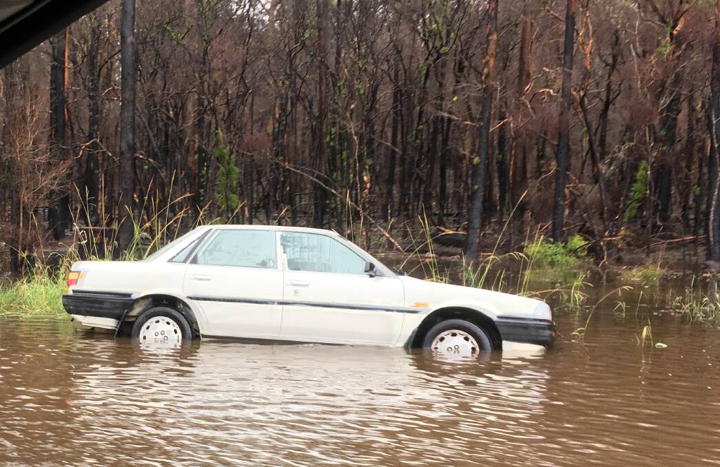 A car in flood waters on Old Bar Road on Sunday. Photo: Nick Brooks